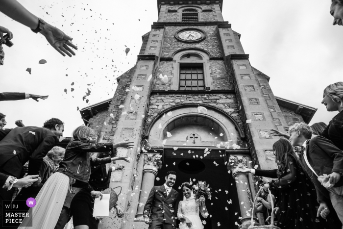 Photo by: <a href="https://www.wpja.com/contests/2019-v18/best-wedding-photographers/2566049">Rocio Vega Roa - Ponferrada Leon</a> Alixan France bride and groom are getting out of the church under a shower of flower petals from their guests.