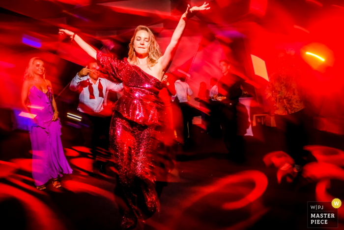 Photo by: <a href="https://www.wpja.com/contests/2019-v18/best-wedding-photographers/2566055">Rocio Vega Roa - Ponferrada Leon</a> A girl in red in a red room dancing and enjoying the party at a Saint Tropez wedding.