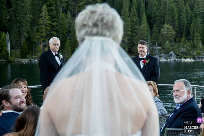 Photo by: <a href="https://www.wpja.com/contests/2019-v18/best-wedding-photographers/2566203">Kevin Sawyer - Lake Tahoe California</a> Safari Rose Boat on South Lake Tahoe - Wedding photography of the Bride walking down aisle during the ceremony with groom and father of bride waiting at the end.