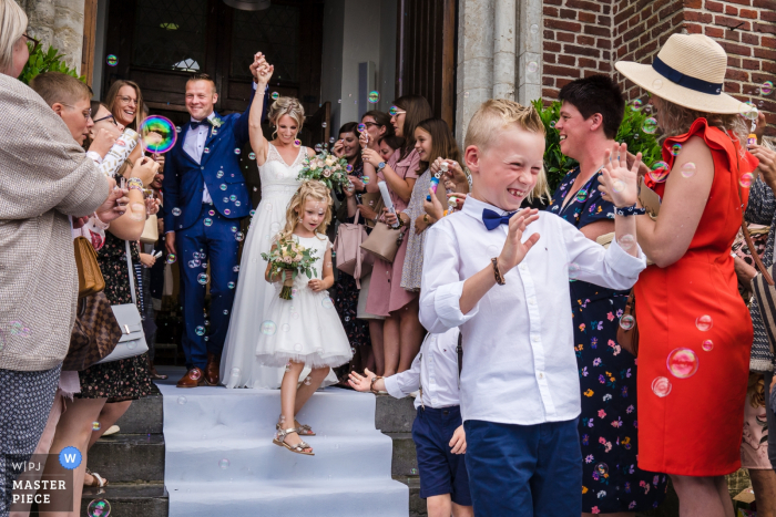 Photo by: <a href="https://www.wpja.com/contests/2019-v18/best-wedding-photographers/2566242">Philippe Swiggers - Bekkevoort </a> Vlaams-Brabant Ceremony Photography - Bride and groom exiting church with guests and bubbles.