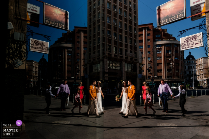 City streets, Bucharest wedding photo | Bride, groom and a few friends walk from the church to the reception venue