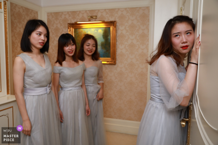 Fujian wedding family picture of a Bridesmaid listening at the door from the groom