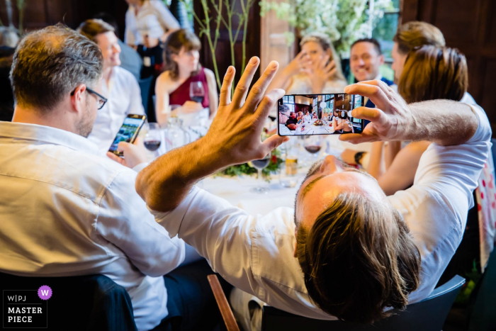 Photo by: <a href="https://www.wpja.com/contests/2019-v18/best-wedding-photographers/2566893">Freek Nagtzaam - 's-Hertogenbosch Noord Brabant</a> Landgoed Rhederoord dinner reception at the wedding. Guest taking photo of the bride and groom at the table.