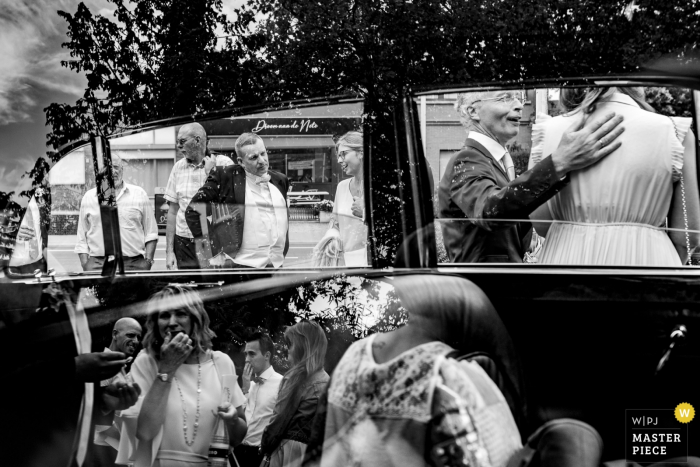 Photo by: <a href="https://www.wpja.com/contests/2019-v18/best-wedding-photographers/2567021">Sanne De Block - Wijnegem Antwerpen</a> Black and white photo of a reflection of wedding guests on a car in Belgium.