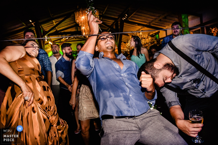 Photo by: <a href="https://www.wpja.com/contests/2019-v18/best-wedding-photographers/2567046">Vinicius Terror - Ouro Preto Minas Gerais</a> Brazil Reception Venue with crazy party and guests doing the limbo with drinks in hand.