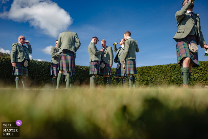 Photo by: <a href="https://www.wpja.com/contests/2019-v18/best-wedding-photographers/2567771">Mike Cook - Larbert Stirlingshire</a> Stirlingshire Scotland Wedding Reception Venue Photography: Groomsmen drinking and attaching buttonholes pre-ceremony