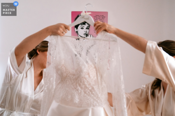 Photo by: <a href="https://www.wpja.com/contests/2019-v18/best-wedding-photographers/2567861">Yves Schepers - Bonheiden Antwerpen</a> Flanders home wedding photography of getting ready: The bride and her bridesmaid prepare the dress while Audrey Hepburn approves