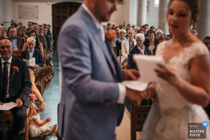 Photo by: <a href="https://www.wpja.com/contests/2019-v18/best-wedding-photographers/2567897">Fille Roelants - Antwerpen Antwerpen</a> Antwerpen Wedding Photographer at the Church: The bride and groom are exchanging vows while their daughter is making a scene in the aisle.