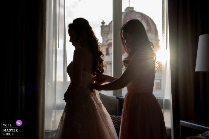Photo by: <a href="https://www.wpja.com/contests/2019-v18/best-wedding-photographers/2567952">Stephanie Secrest - Arroyo Grande California</a> San Francisco hotel getting ready photography before the wedding | Bridesmaid helping bride fasten her dress