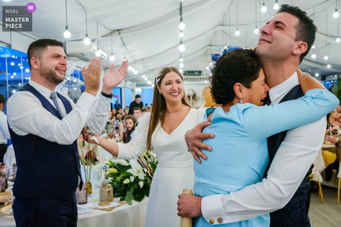 Photo by: <a href="https://www.wpja.com/contests/2019-v19/best-wedding-photographers/2569185">Toni Miranda - Alcoy Alicante</a> Spain wedding reception image of the groom's mother in full emotion holding her son.