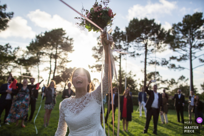 Photo by: <a href="https://www.wpja.com/contests/2019-v19/best-wedding-photographers/2569422">Isabelle Dohin - Andernos les Bains </a> Reception Venue : Tir au Vol Arcachon image contains: Bride throws the bouquet with Ribbons
