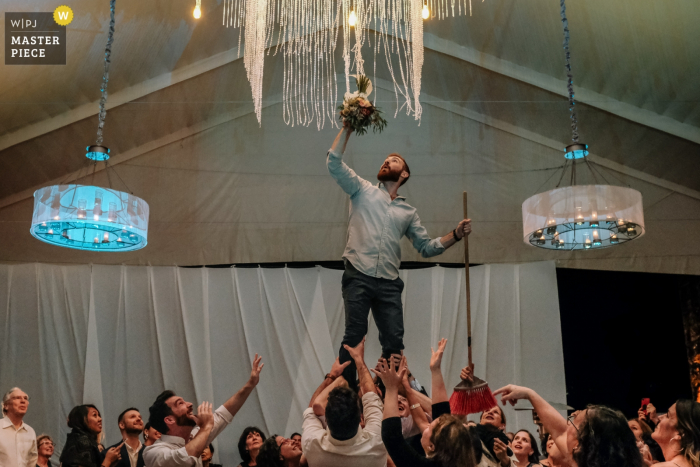 Photo by: <a href="https://www.wpja.com/contests/2019-v19/best-wedding-photographers/2569454">Nikhol Esteras - Oaxaca de Juárez Oaxaca</a> Jardin Etnobotanico, Oaxaca City, Oaxaca, Mexico image contains: Wedding guests rescuing the bouquet stuck in the chandelier
