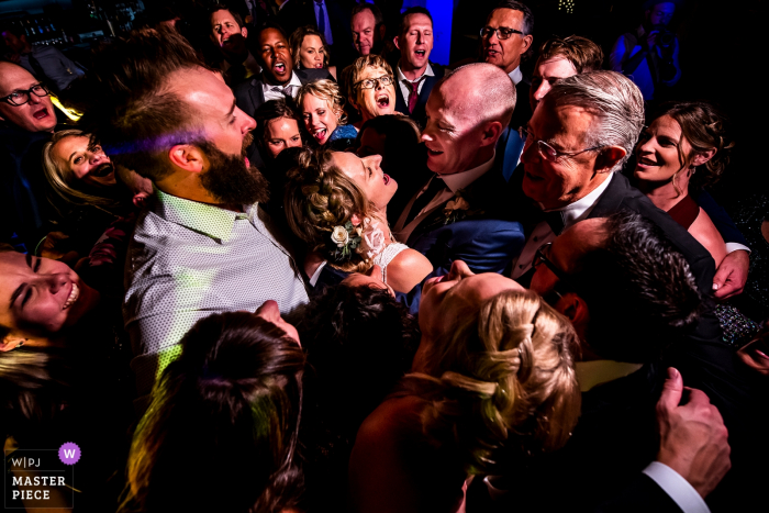 Photographe de mariage Ironworks (Denver, CO): Jeunes mariés faisant un câlin de groupe sur la piste de danse.