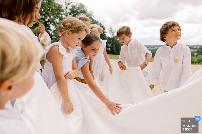 Fotografia di matrimonio di Chateau d'Azy al di fuori di Bambini che giocano con il vestito