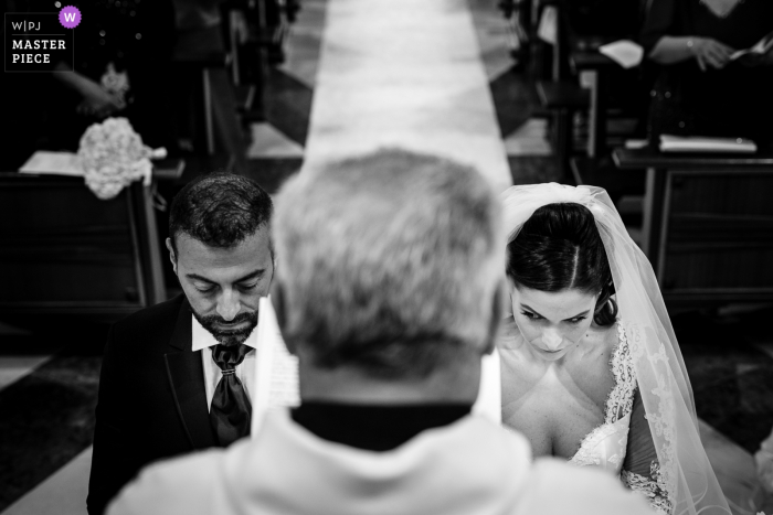 Photo by: <a href="https://www.wpja.com/contests/2019-v19/best-wedding-photographers/2569979">Marco Colonna - Palagiano Taranto</a> Calabria wedding ceremony image of the the bride looking at the groom while the priest blesses them