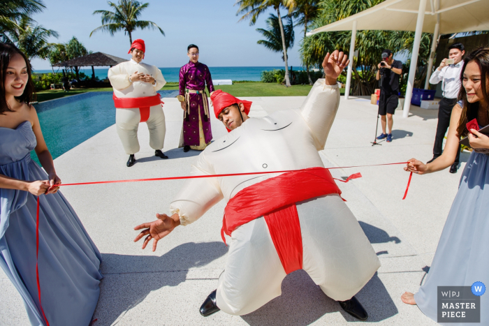 Hochzeitsfoto in Phuket, Thailand: Spielen Sie das Limbo-Spiel im aufblasbaren Sumoringer-Anzug