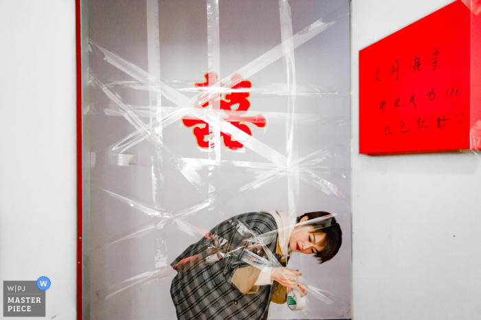 Photo by: <a href="https://www.wpja.com/contests/2019-v19/best-wedding-photographers/2570079">Su Xu - Fuzhou </a> fujian china Wedding moment photography of taping up of the doorway for games