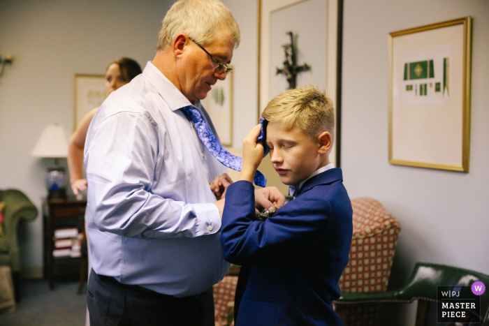 Photo by: <a href="https://www.wpja.com/contests/2019-v19/best-wedding-photographers/2570090">Leah Moyers - Knoxville Tennessee</a> Tennessee Church Wedding Photographer: With no air conditioning in the church basement, the Groom's son grabbed the closest thing to wipe the sweat off his forehead.
