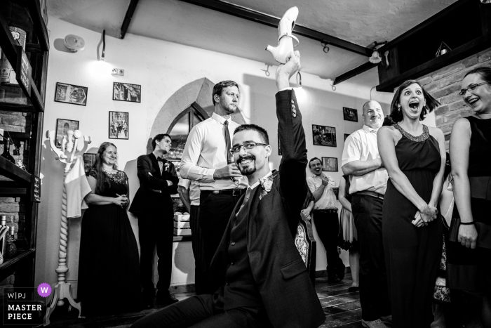 the groom holding up a shoe playing a reception game Barrio Gotico Cafe wedding image of the groom holding up a shoe playing a reception game