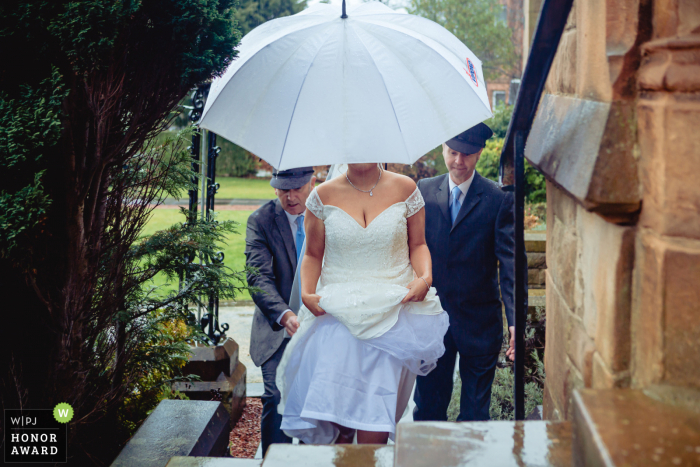 Bride arrives during a downpour of rain Stirlingshire wedding reportage photographer at a church in Scotland - Photo: Bride arrives during a downpour.