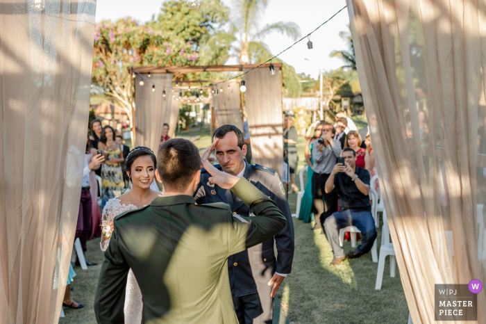 Lugar de la ceremonia de boda al aire libre: Cerimonial Sítio Santa Clara - Aracruz, Espírito Santo, Brasil - Foto del padre de la novia (oficial de la policía de patentes) saludando al novio (oficial del ejército de Brasil)