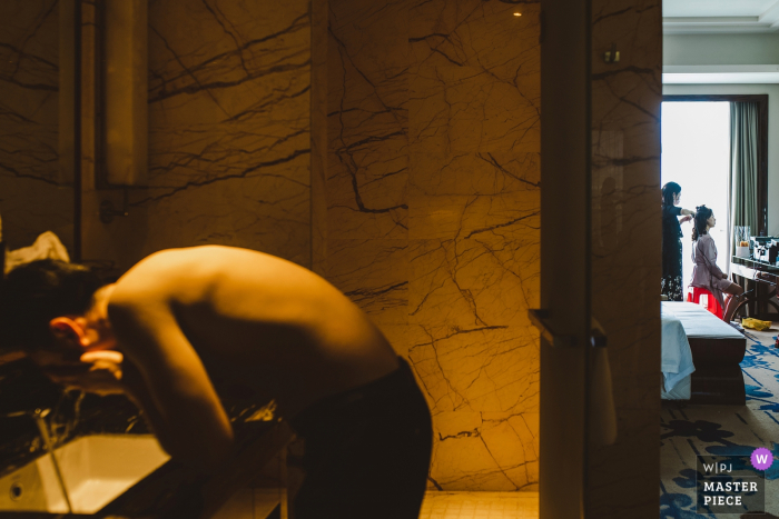the bride being tended to as a gentleman is in the bathroom washing his face Fujian, China getting ready wedding image of the bride being tended to as a gentleman is in the bathroom washing his face