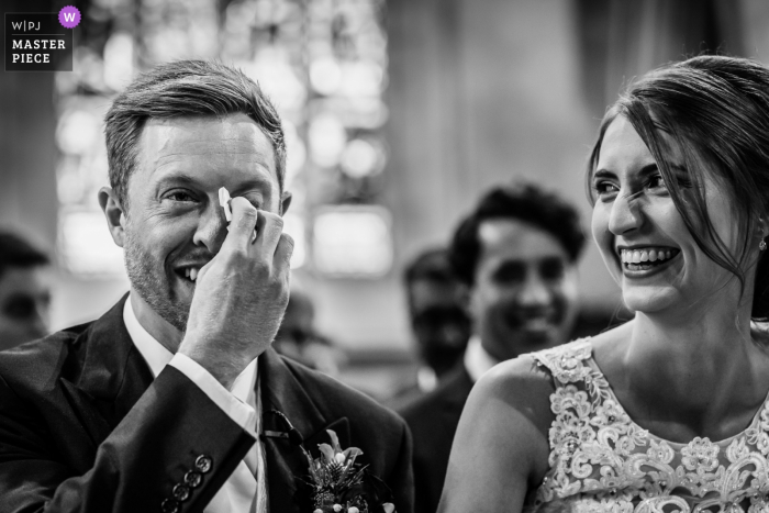 Fotografia de casamento de St Audries Park, Somerset, Reino Unido | Noivo enxugar as lágrimas durante a cerimônia de casamento, enquanto Bride ri dele