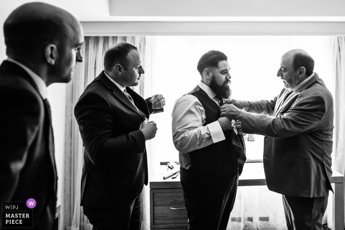 Photo by: <a href="https://www.wpja.com/contests/2019-v19/best-wedding-photographers/2571823">Michelle Arlotta - Milford New Jersey</a> Wedding picture: Father and groomsmen help groom with tie at The Manor, West Orange, New Jersey wedding