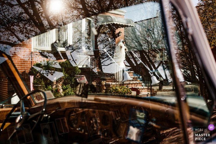 Photo by: <a href="https://www.wpja.com/contests/2019-v19/best-wedding-photographers/2571832">Denis Gostev - New York New York</a> New York City wedding photography: Bride leaves the house, as seen through the front windshield of this vintage wedding transport auto.