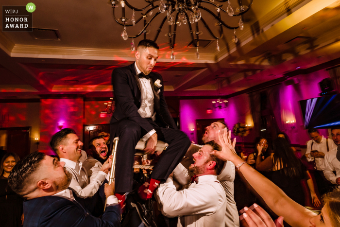Groom is lifted on a chair during the hora dance Wedding Photo from the NY Venue: Royalton on the Greens - Groom is lifted on a chair