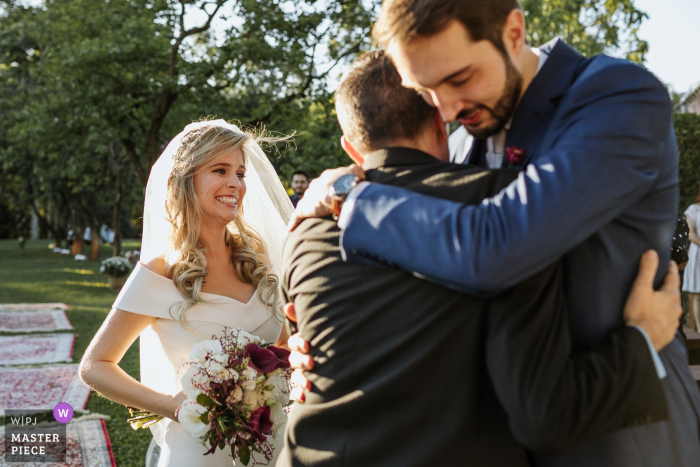 La sposa è entusiasta di vedere il padre abbracciare lo sposo al matrimonio di Cachoerinha