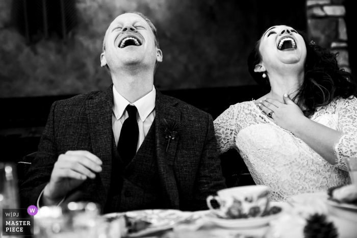 Photo by: <a href="https://www.wpja.com/contests/2019-v20/best-wedding-photographers/2573084">Jesse La Plante - Boulder Colorado</a> Lodge at Cathedral Pines (Colorado Springs, CO) | Bride and groom laughing uncontrollably during the best man's toast.