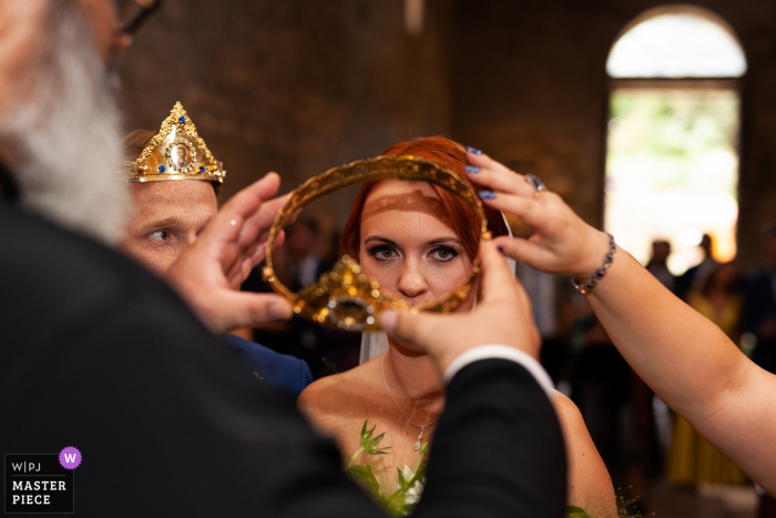 foto di matrimonio abbazia di San Giusto - Tuscania- Italia | La sposa non è molto convinta durante l'incoronazione nella cerimonia ortodossa