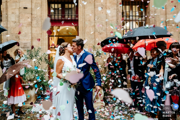 Casamento em Aix-en-Provence | Foto da saída principal para a noiva e o noivo sob guarda-chuvas