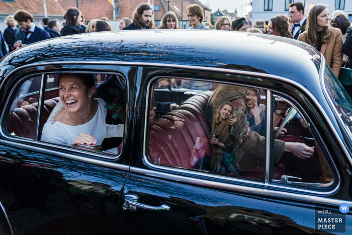 Foto di cerimonia di nozze delle Fiandre | Sposa e sposo a cavallo nella parte posteriore di un'auto.