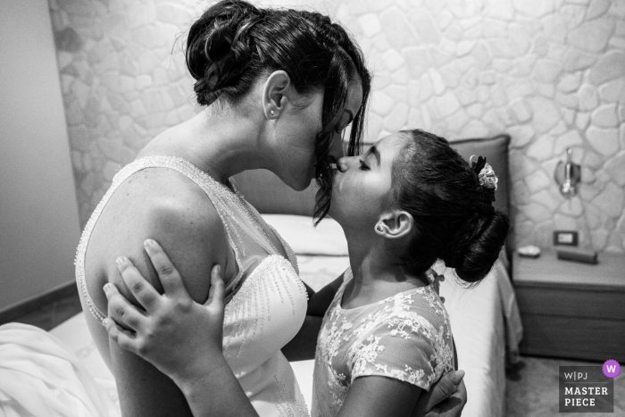 Wedding image of the tender kiss between a little girl and her mom, who will marry a man she loves very much and who will become her dad | Casa della Sposa - Catania