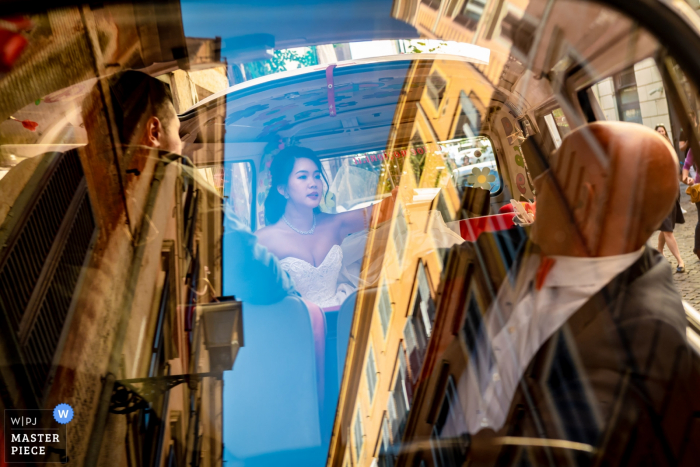 Fotografia do dia do casamento em roma, itália, dentro do carro | Houve a reflexão mostra os edifícios e o céu da cidade no pára-brisa e a noiva estava discutindo com o motorista sobre onde será o próximo destino.