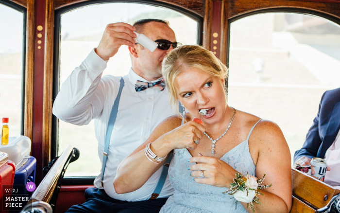 Photo by: <a href="https://www.wpja.com/contests/2019-v20/best-wedding-photographers/2575506">Andrea Bibeault - Omaha Nebraska</a> Ollie the Trolley, Omaha, NE (party bus) | Bridesmaid opening a bottle of Fireball with her teeth! Groomsman passing out more shots of Fireball