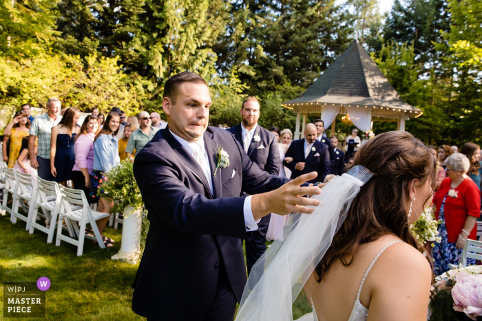 Chattaroy, Washington trouwfoto's van buitenceremonie | Bruidegom reageert op het uitvallen van de sluier van zijn bruid na de ceremonie.