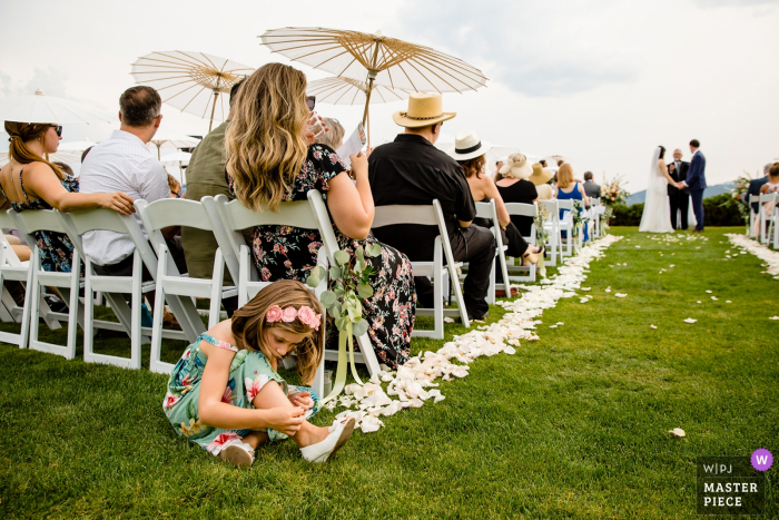 Um jovem casamento convidados se diverte Fotografia de cerimônia de casamento ao ar livre de Coeur d'Alene, Idaho | Uma jovem convidada de casamento se diverte durante a cerimônia.