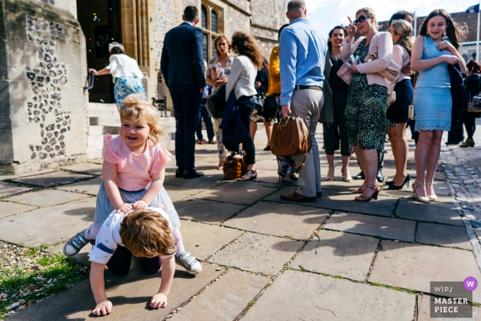 A little girl riding her brother Winchester Registry Office wedding reportage | A little girl riding her brother whilst guests exit ceremony location