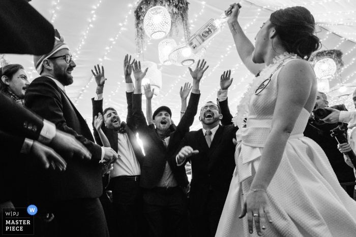 Alcoy wedding photo of the bride holding a bottle of liquor up to her friends at the reception.