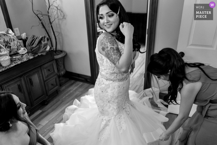 Grand Tradition Estate and Gardens, Fallbrook, CA venue photography | The bridesmaids help the bride into her wedding dress.