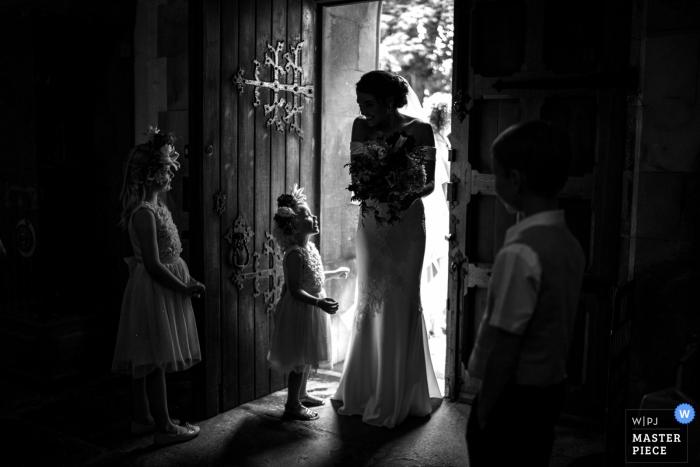 Wimborne Minster, Dorset trouwreportage fotografie Flower Girl wenst bruid geluk als ze arriveert om te trouwen