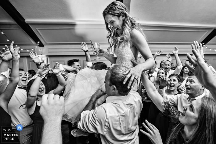 Photo by: <a href="https://www.wpja.com/contests/2019-v20/best-wedding-photographers/2576872">Michelle Arlotta - Milford New Jersey</a> Bride gets lifted into the air during reception at Lake Mohawk Country Club New Jersey wedding