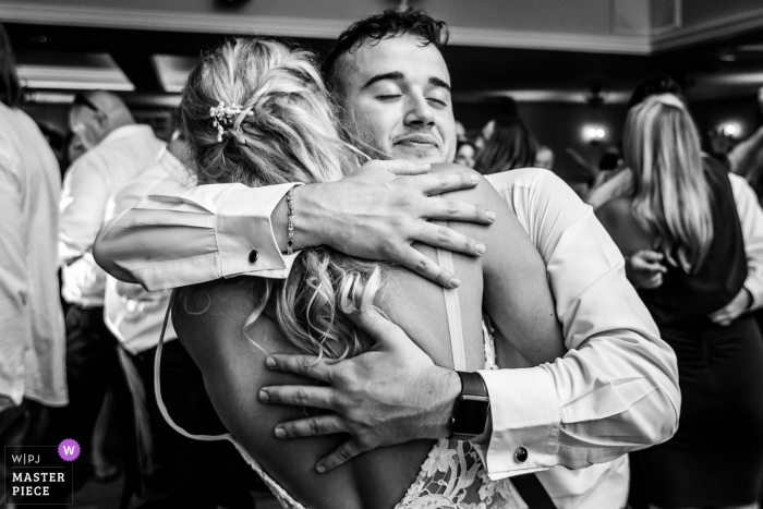 Brother of the groom hugs bride tightly on dance floor during Bear Brook Valley NJ wedding