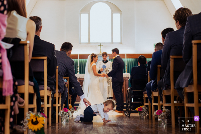 Bricket Wood - fotos de casamento no Reino Unido | Uma criança no corredor durante a cerimônia