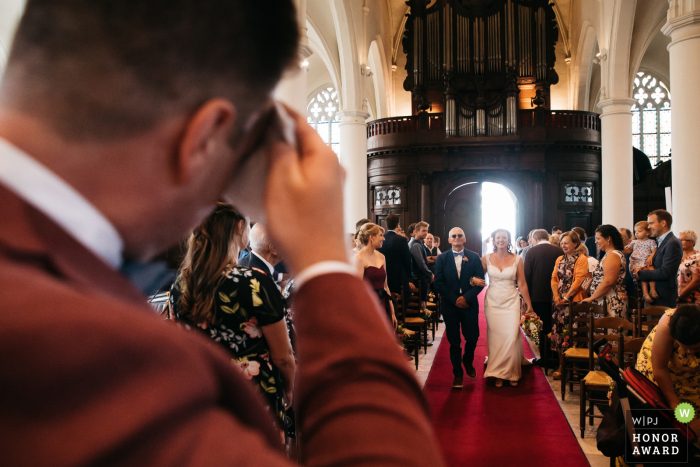 Hochzeitsfotojournalismus in der Kirche von Antwerpen - Der Bräutigam wischt sich die Stirn, als er beim Eintritt seiner zukünftigen Frau in die Kirche stark schwitzt.