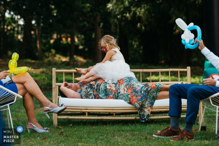 Flanders reception venue photography | A kid is trying to catch her grandmother's attention while she is trying to take a nap between 2 receptions.