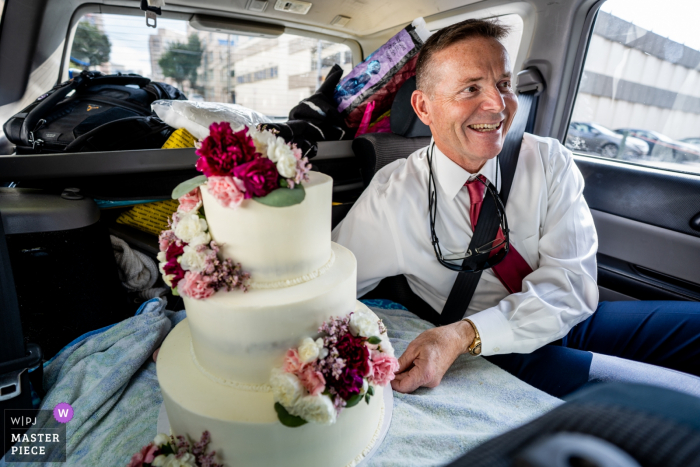 Sanctuaire de Woodend, photographie de mariage de Chevy Chase MD | Le père de la mariée monte sur la banquette arrière de la voiture avec le gâteau à trois étages que sa fille, la mariée, a fabriqué de toutes pièces.